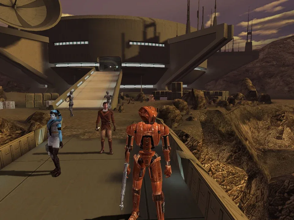 Blue humanoid, human, and orange droid stand before desert base with purple sky.