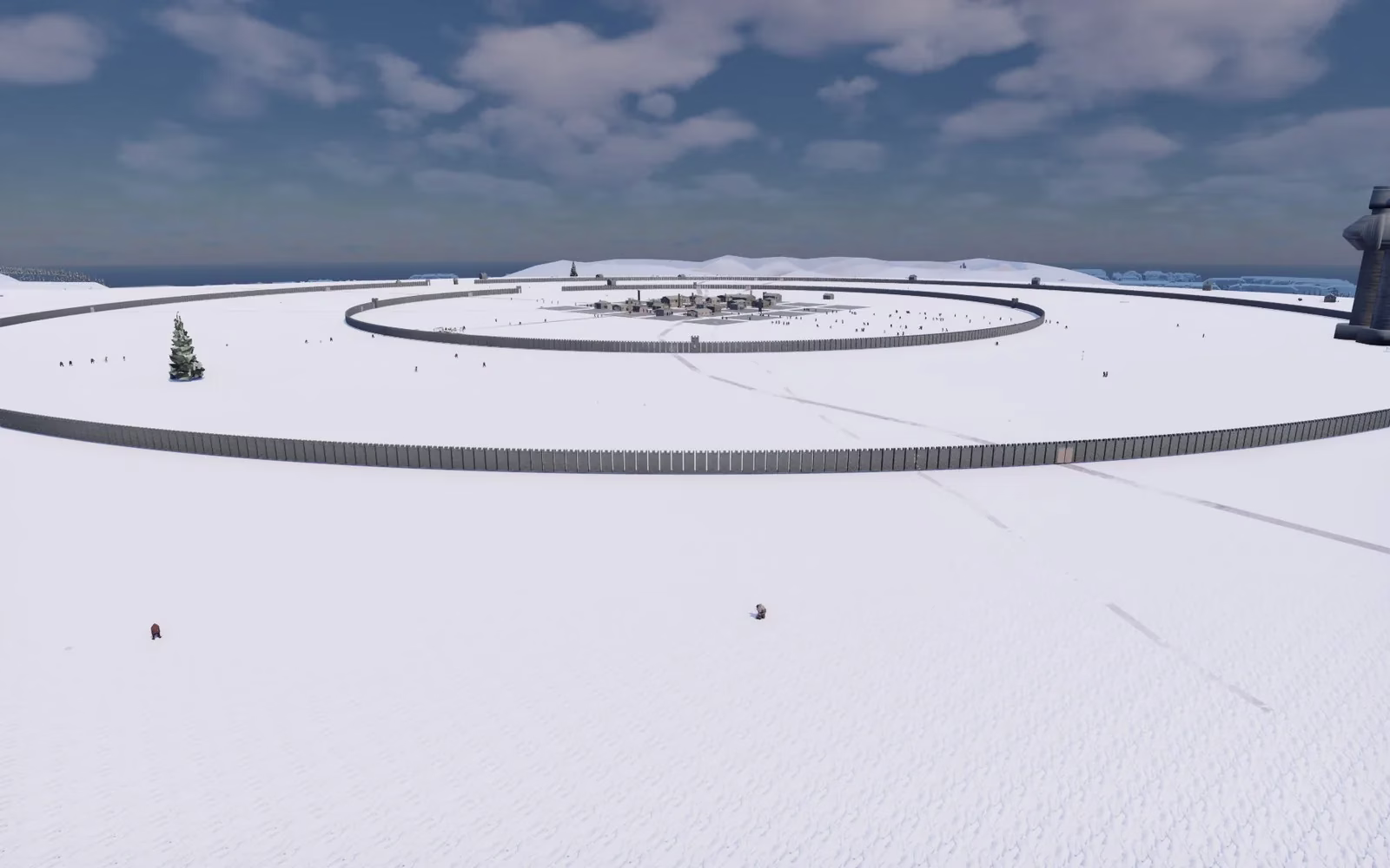 A wide snowy plain with two huge ring-shaped palisade walls, a small cluster of grey houses in the middle, a few tiny figures in the snow, and dark water on the horizon.