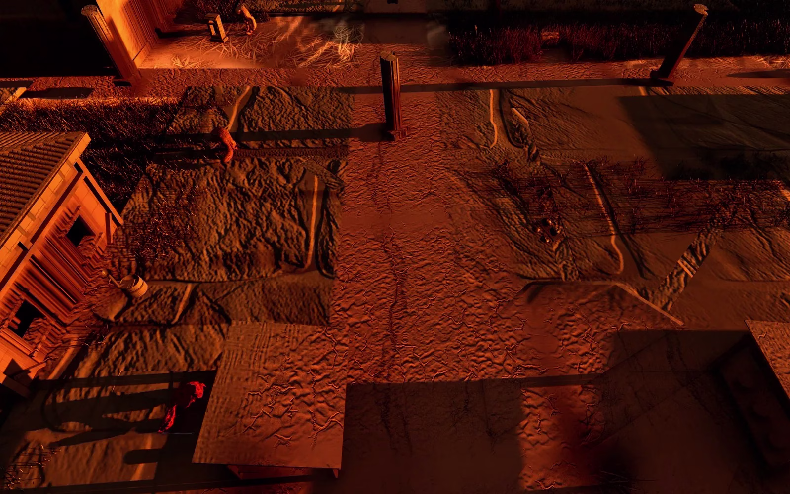 A town street seen from above at dusk in warm orange light, with square dirt plots, a lone stone column, a house with a tiled roof on the left and a few small figures.